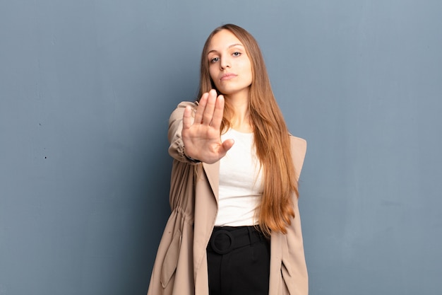 looking serious, stern, displeased and angry showing open palm making stop gesture