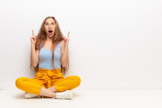 looking shocked, amazed and open mouthed, pointing upwards with both hands