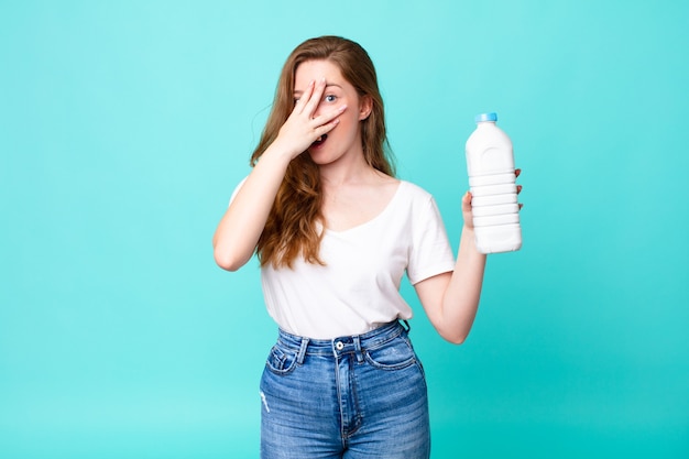 Looking shocked, scared or terrified, covering face with hand and holding a milk bottle