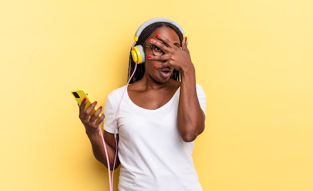 Looking shocked, scared or terrified, covering face with hand and peeking between fingers and listening music