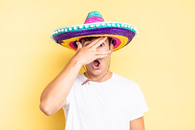 Looking shocked scared or terrified covering face with hand and peeking between fingers mexican hat concept