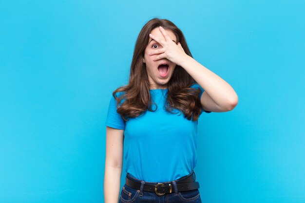 looking shocked, scared or terrified, covering face with hand and peeking between fingers