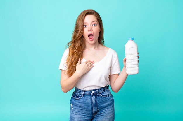 Looking shocked and surprised with mouth wide open, pointing to self and holding a milk bottle