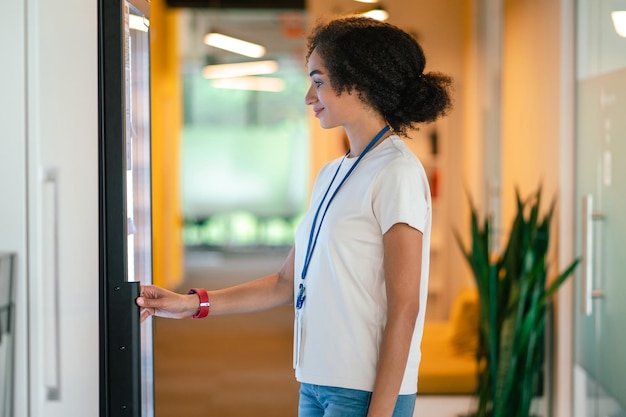 looking for a snack. young woman choosing something from the fridge in the office canteen