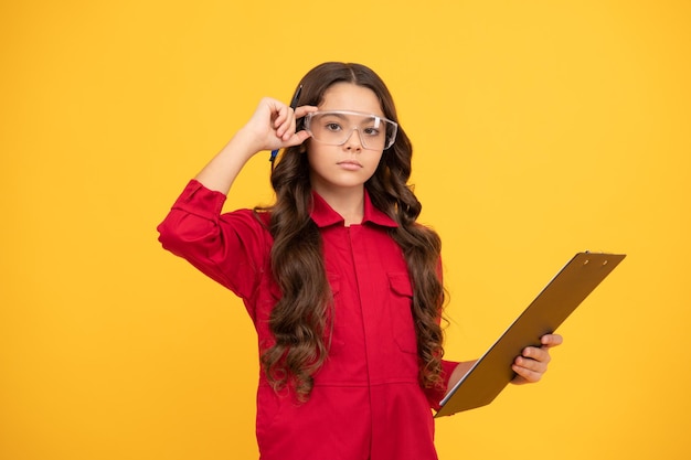 Looking so smart. teen girl wear eyeglasses. kid make notes in folder on yellow background. child study at school. work with documents. serious kid in protective glasses. childhood.