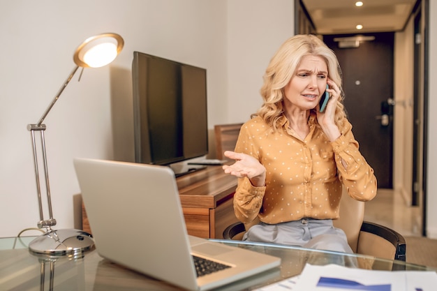 Looking stressed. Blonde pretty woman sitting talking on the phone and looking stressed