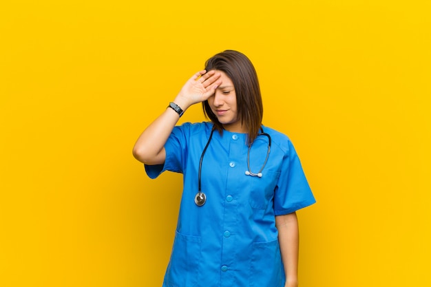 Photo looking stressed, tired and frustrated, drying sweat off forehead, feeling hopeless and exhausted isolated against yellow wall