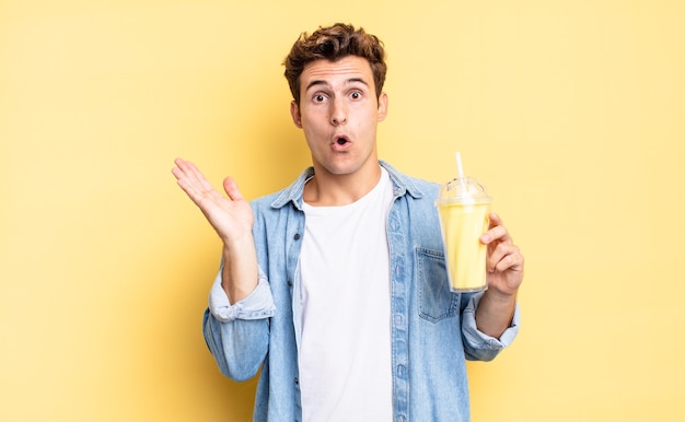 Looking surprised and shocked, with jaw dropped holding an object with an open hand on the side. milkshake concept