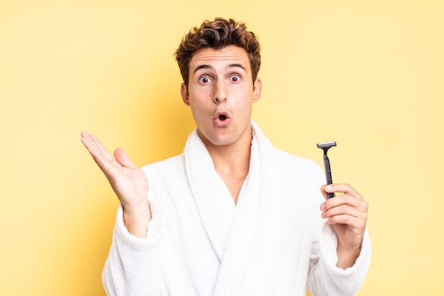 Looking surprised and shocked, with jaw dropped holding an object with an open hand on the side. shave concept