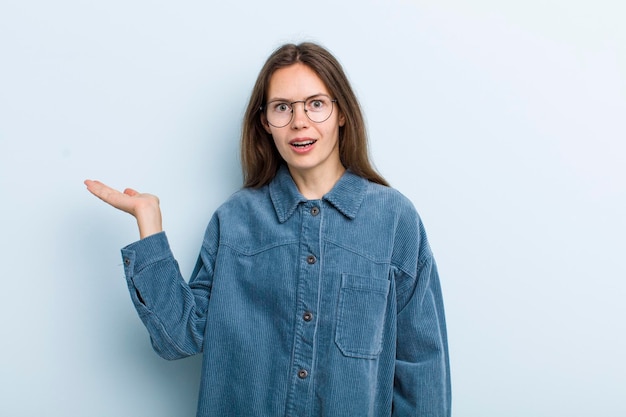 Looking surprised and shocked with jaw dropped holding an object with an open hand on the side