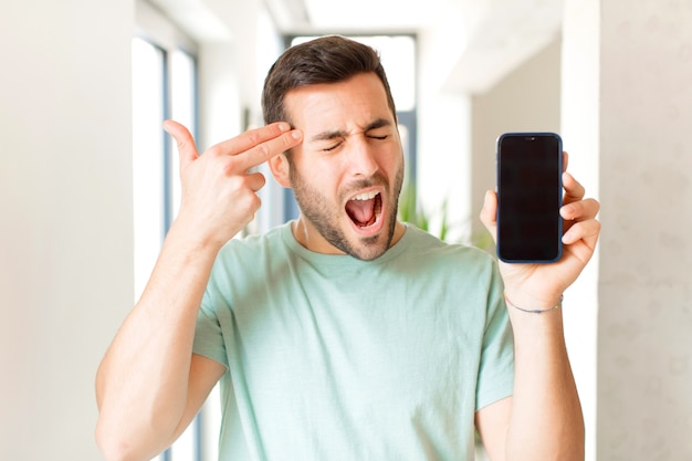 looking unhappy and stressed, suicide gesture making gun sign with hand, pointing to head