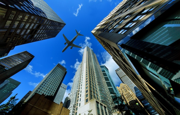 Photo looking up at new york city skyscrapers in financial district, nyc usa plane flying