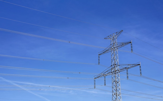 Looking up to steel electricity pylon against blue sky with only few clouds streaks