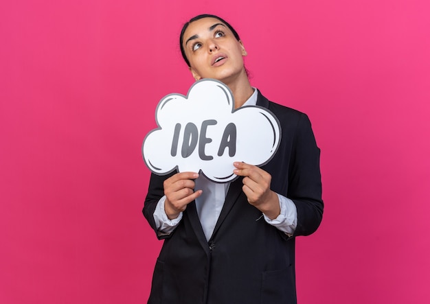 Looking up young beautiful woman wearing black blazer holding idea bubble 