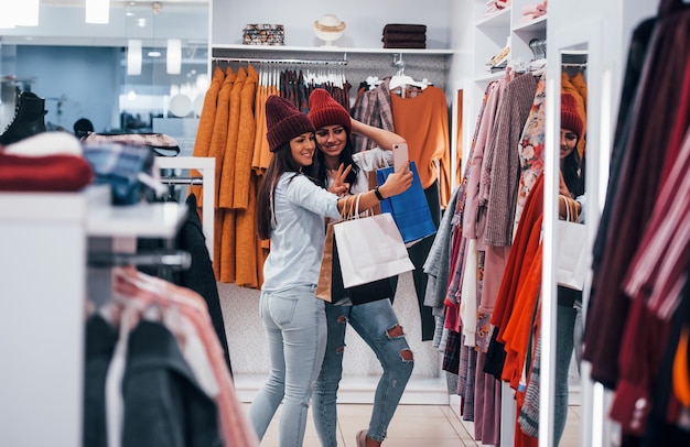 Ищу теплую одежду. Две молодые женщины вместе проводят день покупок в супермаркете.