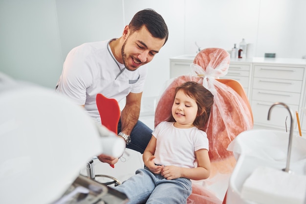 Looks into the mirror Little girl visiting dentist in clinic Conception of stomatology