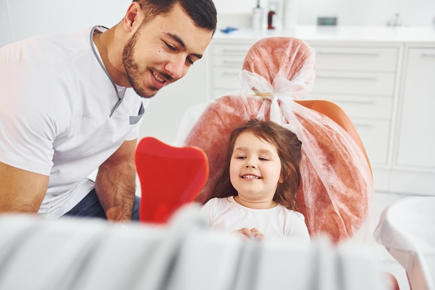 Looks into the mirror Little girl visiting dentist in clinic Conception of stomatology