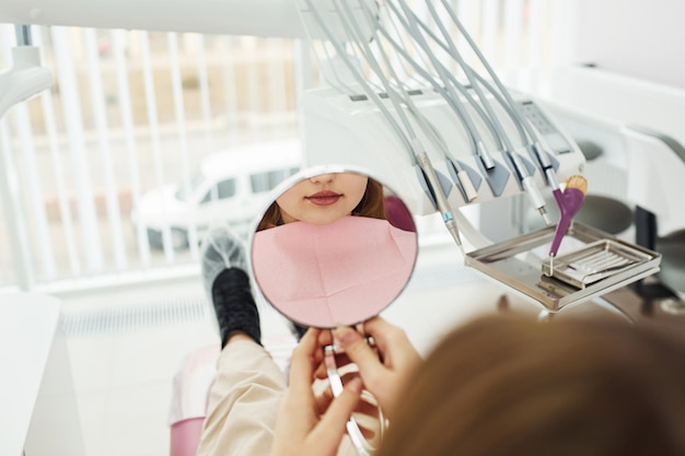 looks at mirror little girl visiting dentist in clinic conception of stomatology