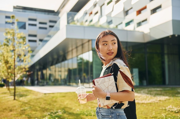 Looks behind Young asian woman is outdoors at daytime