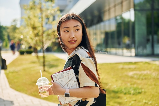 Looks behind Young asian woman is outdoors at daytime