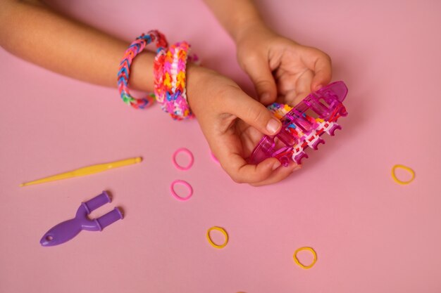 Il telaio per tessere braccialetti giocattolo da elastici è tenuto da un bambino nelle sue mani