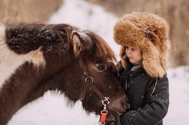 Loop in de winter over sneeuwpaden tussen het riet van de pony en de baby