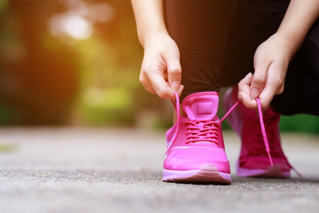 Loopschoenen roze close-up vrouwelijke atleet veters vastbinden om te joggen op de weg Runner stropdassen klaar voor training Sport levensstijl