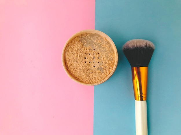 Loose powder on a bright background next to a powder makeup brush powder brush fluffy