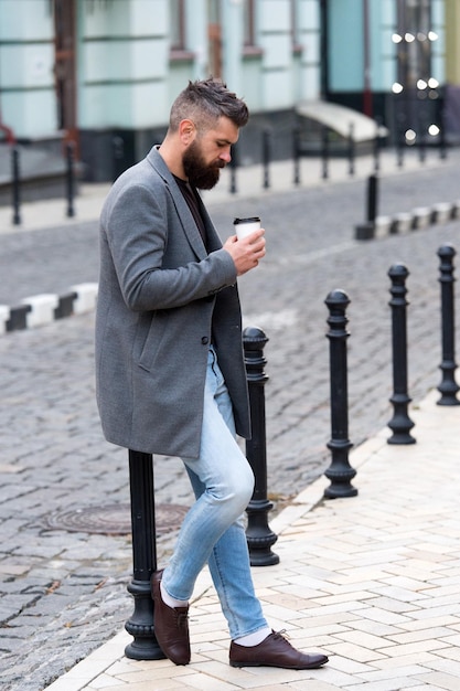 Lopen en genieten van verse warme koffie Wachten op iemand in de straat Man bebaarde hipster drinken koffie papieren beker Zakenman goed verzorgd genieten van koffiepauze buiten stedelijke achtergrond Genieten van koffietijd