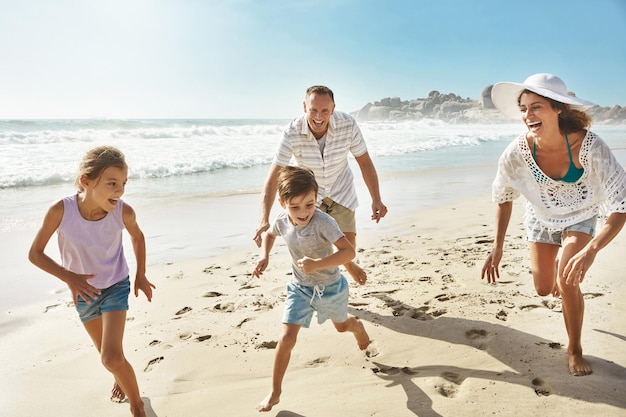 Lopen spelen en gelukkig gezin op een strand met plezier binding en vrijheid op zomervakantie en vakantie Reizen energie of opgewonden kinderen met ouders bij de oceaan voor avontuur reis of race in Bali