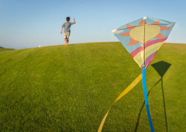 Lopend met vlieger op de vakantie van de de zomervakantie, perfecte weide en hemel op kust