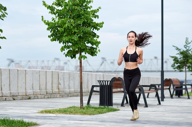 Lopende Aziatische vrouw aan de waterkant Ochtend joggen De atleet traint