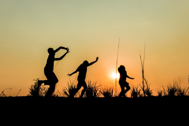 Lopende groep kinderen die op weide, zonsondergang, silhouet lopen