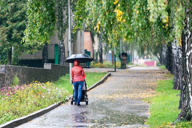 Lopende vrouw met kinderwagen genieten van zomerdag in park Joggen of power walking supermom actieve familie met baby jogger