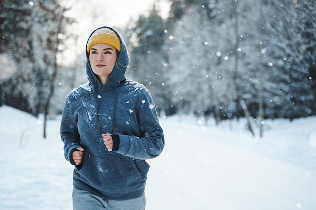 Lopende vrouw tijdens haar joggingtraining tijdens de winter en besneeuwde dag