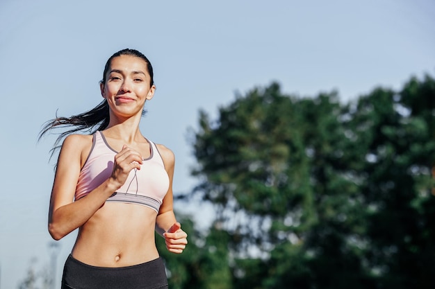 Lopende vrouw vrouwelijke runner joggen tijdens outdoor workout in een park mooie fit meisje fitness model buitenshuis gewichtsverlies