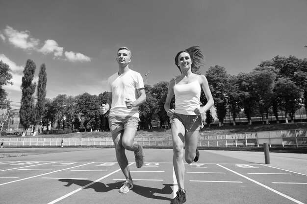 Loper op competitie en toekomstig succes Man en vrouw zonnig buiten op blauwe hemel Paar uitgevoerd op arena track Sport en gezonde fitness Coach en trainer bij training