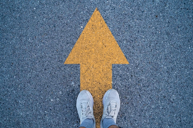 Foto loper staan op asfalt weg met gele pijl voor gaan vooruit en nooit opgeven om te rennen het zal gebruiken in conceptuele van zakelijke levensstijl