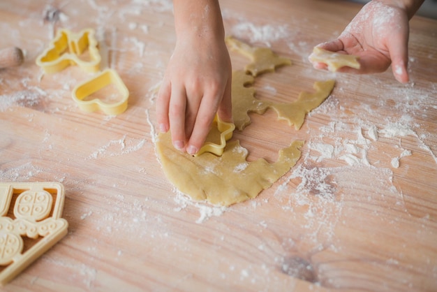 Ð¡lose up of kid hands making fresh dough cookies at home.