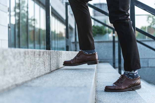  Ð¡lose-up of male legs in business trousers and shoes walking up the stairs