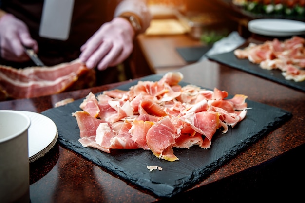 loseup of small thin slices of spanish jamonon black cutting board