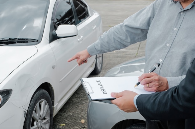 Agente assicurativo perito assicurativo che ispeziona il responsabile delle vendite di auto danneggiate che fornisce consigli