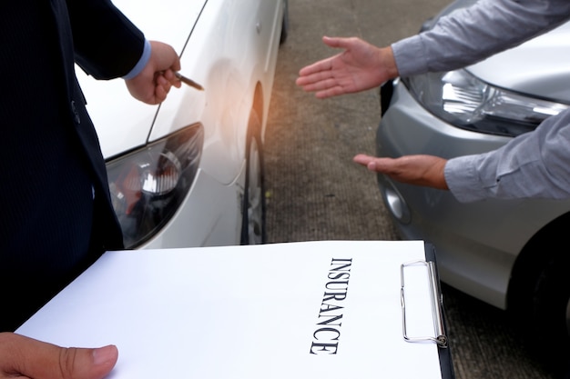 Photo loss adjuster insurance agent inspecting damaged car.