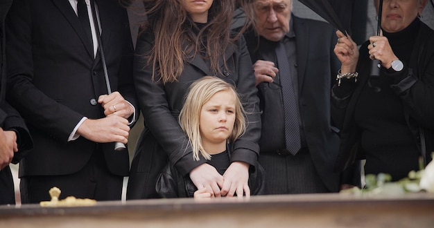 Foto perdita dolore e persone al funerale con fiori ombrello e bara famiglia con bambino triste al servizio nel cimitero rose morte e gruppo in pioggia al bara in cimitero con il bambino alla tomba per la sepoltura