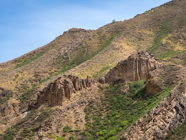 Losse steen. Sfeervol landschap met rotsachtige bergwand met puntige top in zonnig licht. Losse stenen berghelling op de voorgrond. Scherpe steenachtige bergen.