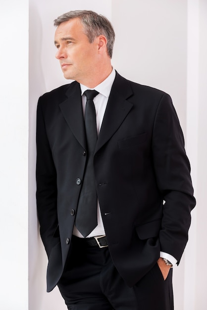Photo lost in business thoughts. thoughtful mature man in formalwear looking away while leaning at the wall