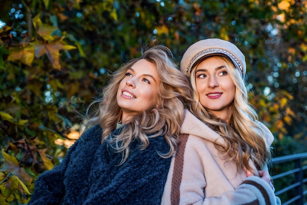 Lost in thoughts autumn fashion and beauty pretty girls has long curly blond hair ladies in fall clothing in autumn forest or park female friendship beautiful blonde women in coat