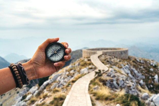 Photo lost woman on the mountain, orienting herself with a compass. find a solution.