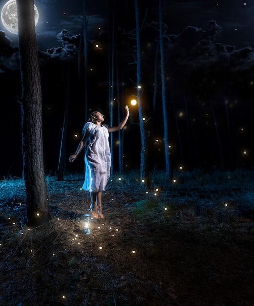 Foto giovane donna persa nella foresta notturna con la luna piena che salta in alto per raggiungere la lucciola