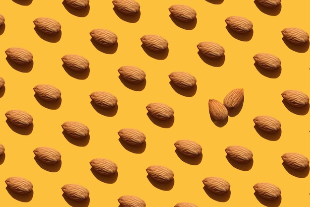 Photo a lot of almonds on an orange background nuts pattern